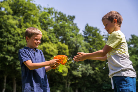 Kids playing, shooting with soap bubbles during hot weather