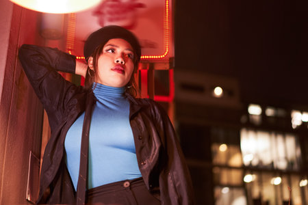 Stylish brunette woman in trendy clothes looking distance enjoying nightlifeの写真素材