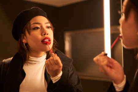 Brunette asian woman with natural makeup looking attentively at the mirrorの写真素材