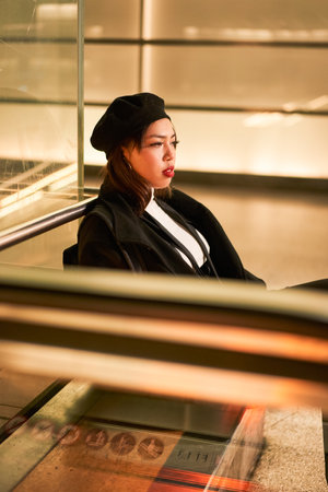 Young woman wearing black hat sitting at the tram station and looking distanceの写真素材