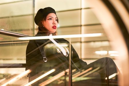 Serious asian girl looking away and sitting at the bus station aloneの写真素材