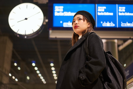 Asian calm woman standing in terminal against electronic board