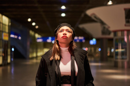 Young woman standing at international airport against timetable and lookingの写真素材