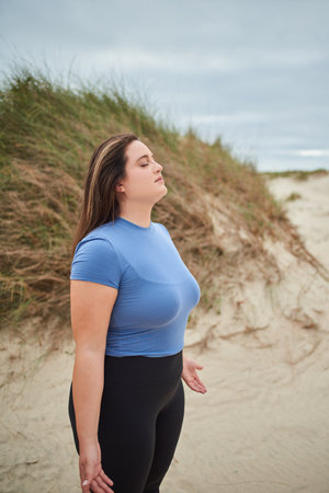Caucasian plus size woman in sportive clothes closed eyes and breathing deeplyの写真素材