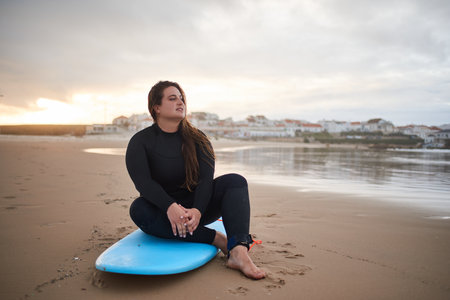 Full length view of the romantic overweight surfer woman looking at the oceanの写真素材