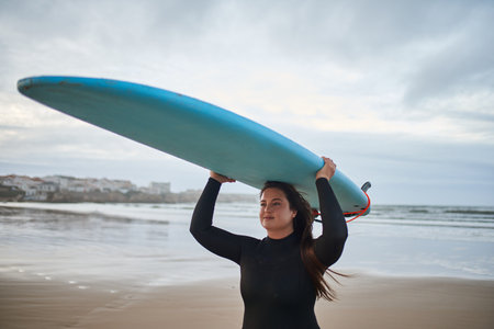 Cute body positive woman carrying surfboard on head and enjoying of the summerの写真素材