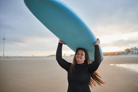 Female surfer holding board at her head and enjoying the view over the bayの写真素材