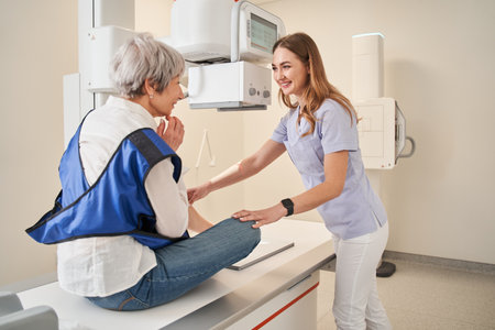 Careful nurse talking with senior lady patient during x ray examination at modern clinicの写真素材