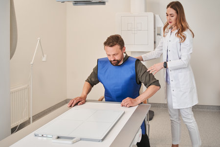 Careful nurse talking with man patient during x ray examination at modern clinicの写真素材