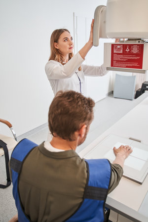 Nurse woman scanning man patient hand on modern X-ray scannerの写真素材