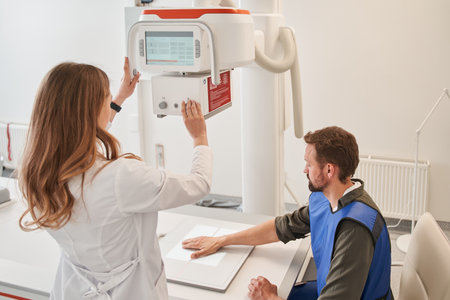 Female physician turning x ray machine for making check up for man patient at the clinicの写真素材