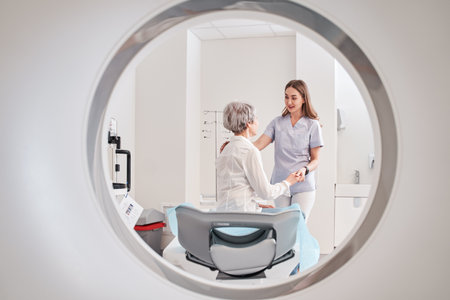 Lady radiographer talking with female patient after operating CT scanner at hospitalの写真素材