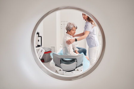Hospital radiographer with female patient operating CT scannerの写真素材