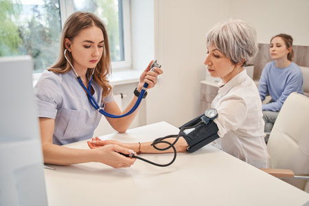 Young female medical worker measuring arterial blood pressureの写真素材