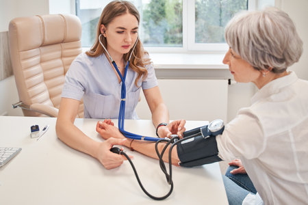 Young female medical worker measuring arterial blood pressureの写真素材