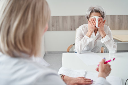 Anxious senior woman crying on chair at the therapist officeの写真素材