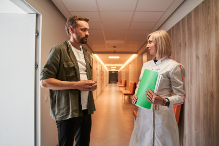 Worried man patient talking with his female doctor at the hall of the clinicの写真素材