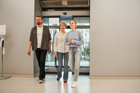 Smiling senior woman and her adult kids entering at the hospital