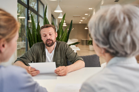Mature woman and her adult kids sitting and signing medical agreementの写真素材