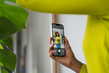 Cropped view of the woman standing in front of the mirror and making smartphone selfie
