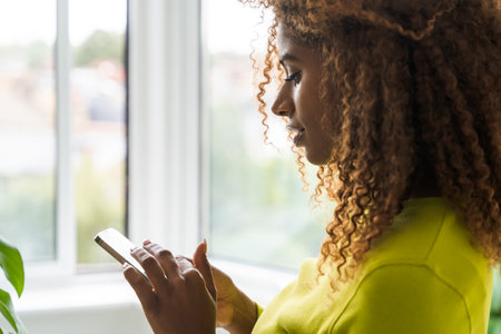 Closeup curly african american woman holding smartphone and typing messageの写真素材