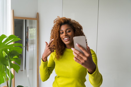 Multiracial happy woman video calling smartphone and looking awayの写真素材