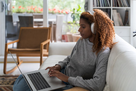 Attractive african american woman is using a computer and listening musicの写真素材