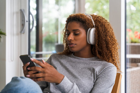 Brunette multiracial woman wearing casual home clothes resting on armchairの写真素材