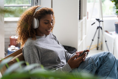 Brunette multiracial woman wearing casual home clothes resting on armchairの写真素材