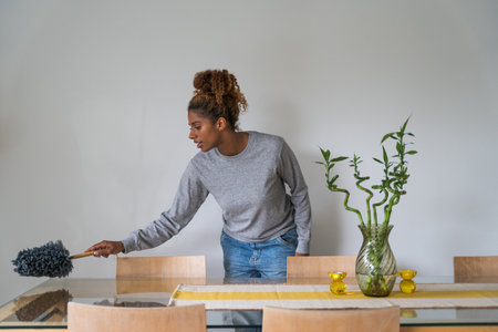Joyful african american woman cleaning room with broomの写真素材