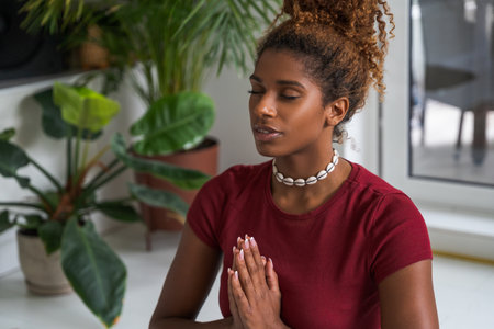 Waist up portrait view of woman meditating with closed eyes and hands in prayer gesture