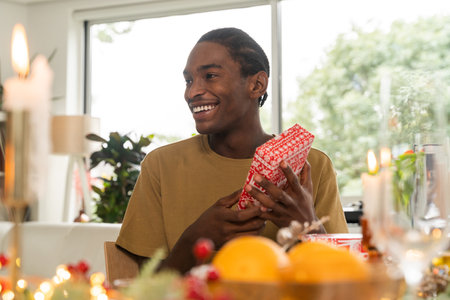 Positive multiracial man holding present box while recieving New Year giftの写真素材