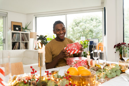 Positive multiracial man holding present box while recieving New Year giftの写真素材