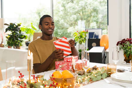 Happy african american man recieving gift from loving womanの写真素材