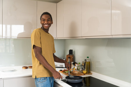 Happy african american man looking with smile while cookingの写真素材