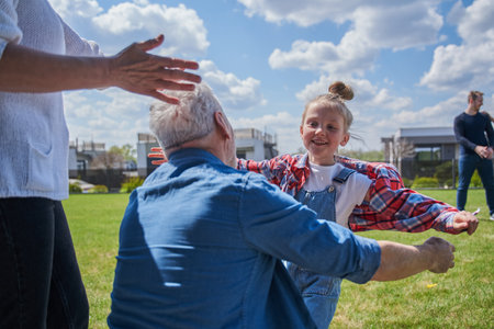Small child girl embracing her senior grandfather while meeting himの写真素材