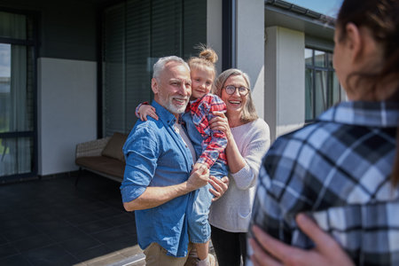 Senior couple holding little girl at the hands and feeling happy at the summer
