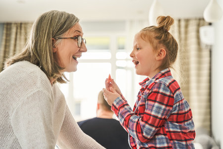 Cheerful mature woman in eyeglasses having fun with her granddaughterの写真素材