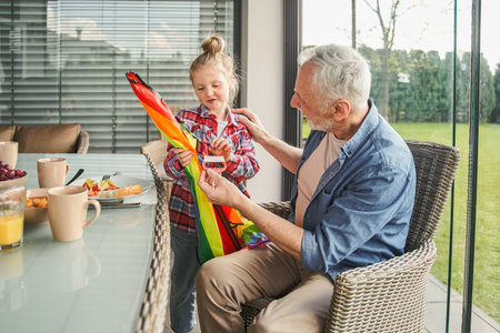 Little cute girl holding kite and speaking with her grandfather while playingの写真素材