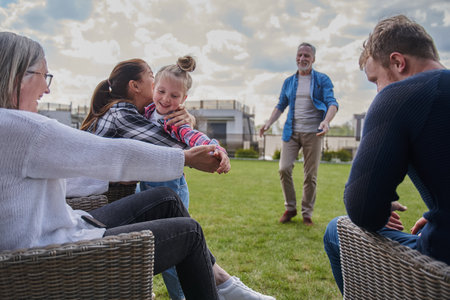 Full-length view of the cheerful family with kid girl playing at the grassy meadowの写真素材