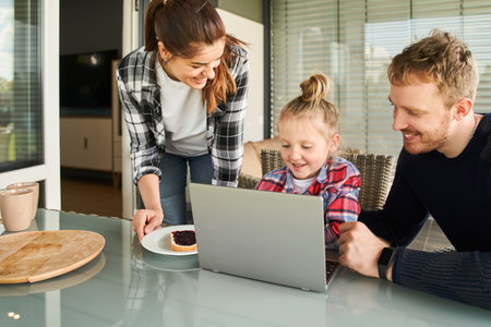 Cheerful mother bringing sandwich to her little daughterの写真素材