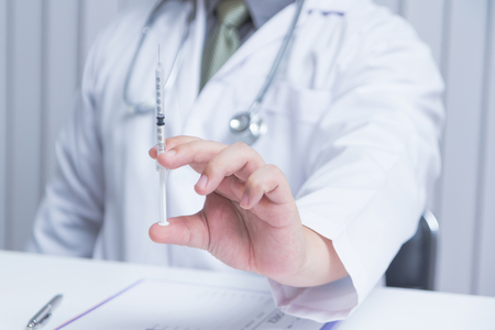 Doctor holding an injection needle in his outstretched hand. - Health care conceptの写真素材