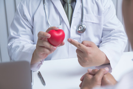Doctor and patient are discussing something with stethoscope and red hart in hand.- Health care conceptの写真素材