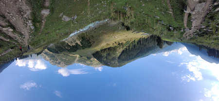 Panoramic view of the alpine lake with reflection in the water