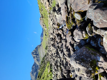 rocky mountain with green moss on it and blue sky in summerの写真素材