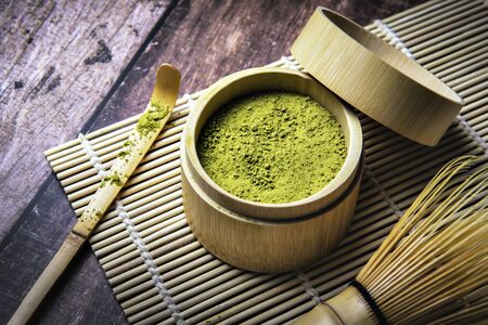 Green Tea Matcha Powder in the Bamboo Cup with Wooden Chasen and Wooden Spoon and on Wooden Backgroundの写真素材