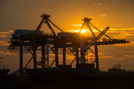 Industrial Container Cargo freight ship with working crane bridge in shipyard at dusk for Logistic Import Export backgroundの写真素材