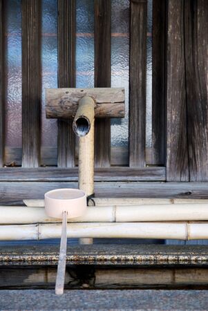 Japanese style bamboo water pipe and plastic dipper in a templeの写真素材