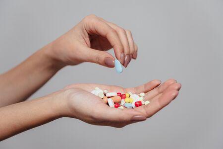 Girl holds a handful of pills in her hand. Takes one tablet.