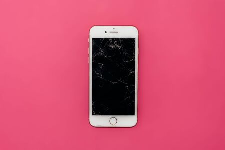 Smartphone with broken glass on a pink background.の写真素材